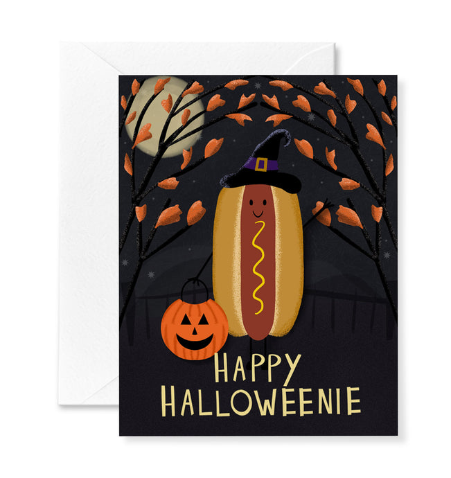 Halloween-themed card with a hot dog in a witch hat and pumpkin, set against a dark background with a moon and leaves.