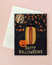 Halloween-themed card with a hot dog wearing a witch hat, pumpkin, and 'Happy Halloweenie' text on a black background.