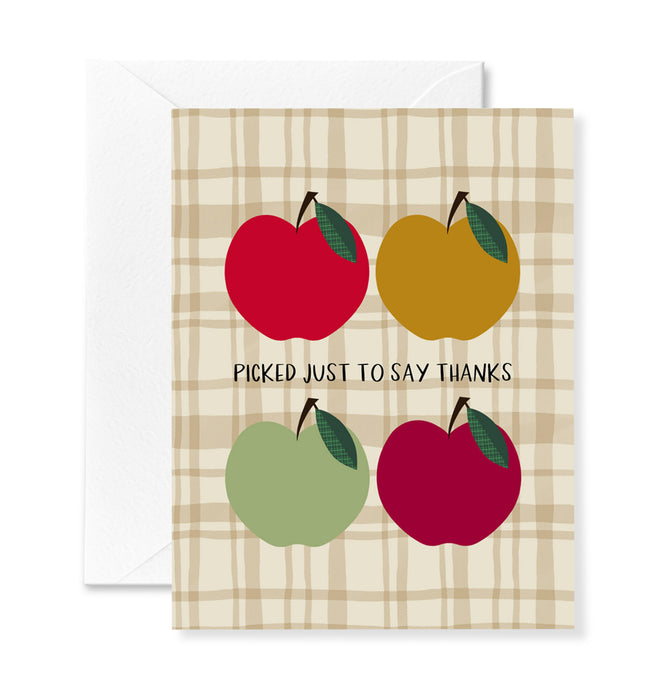 Greeting card with red, yellow, and green apples on a plaid background